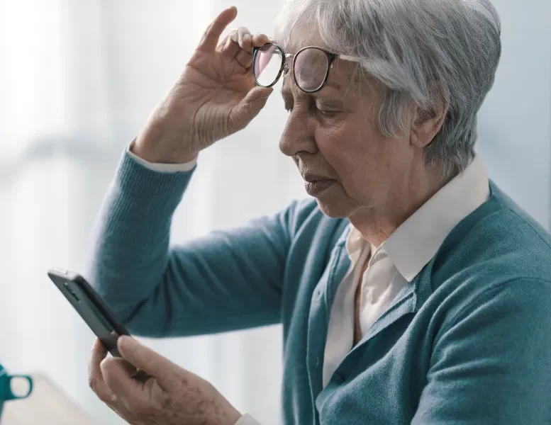Senior woman having vision problems, she can't read the messages on her smartphone