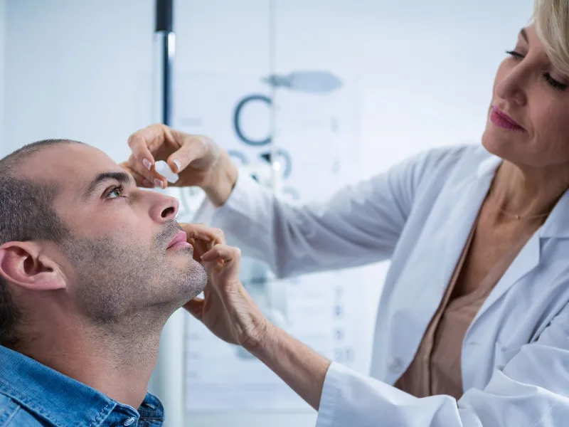 Optometrist putting drops into patients eyes in ophthalmology clinic