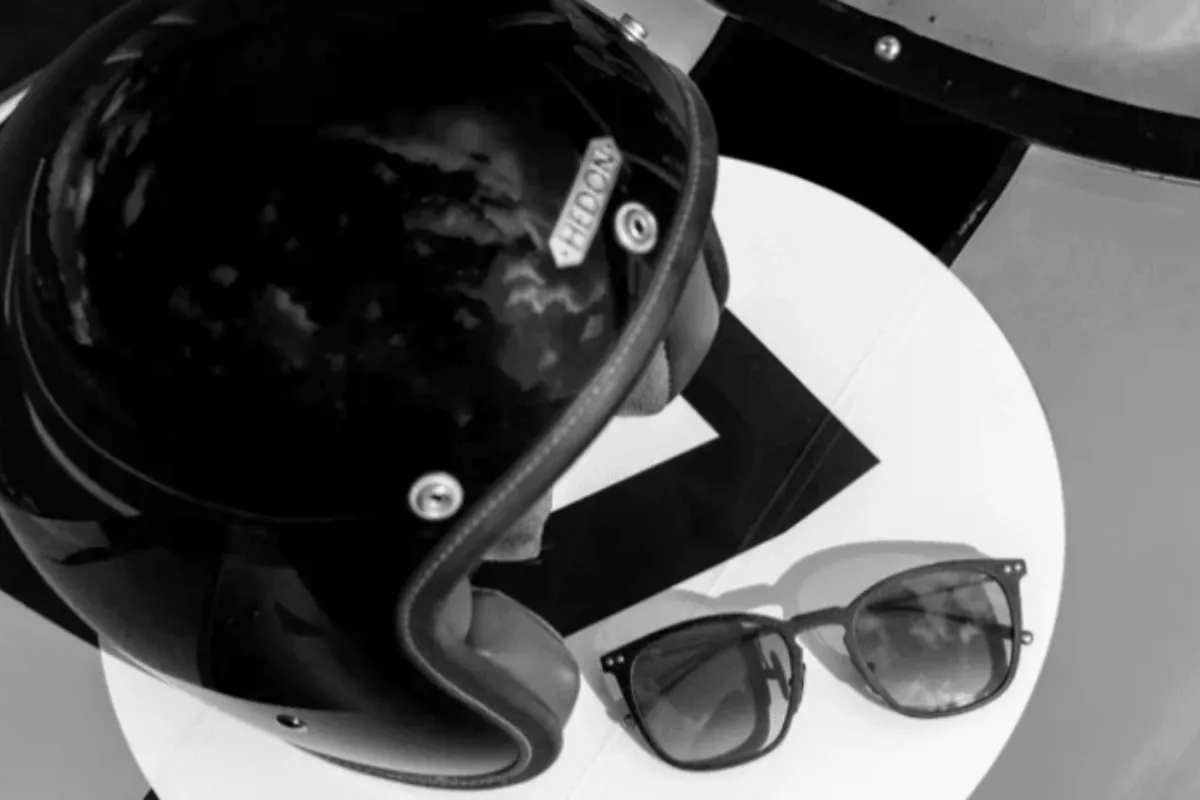 Black motorcycle helmet and sunglasses on a white table.