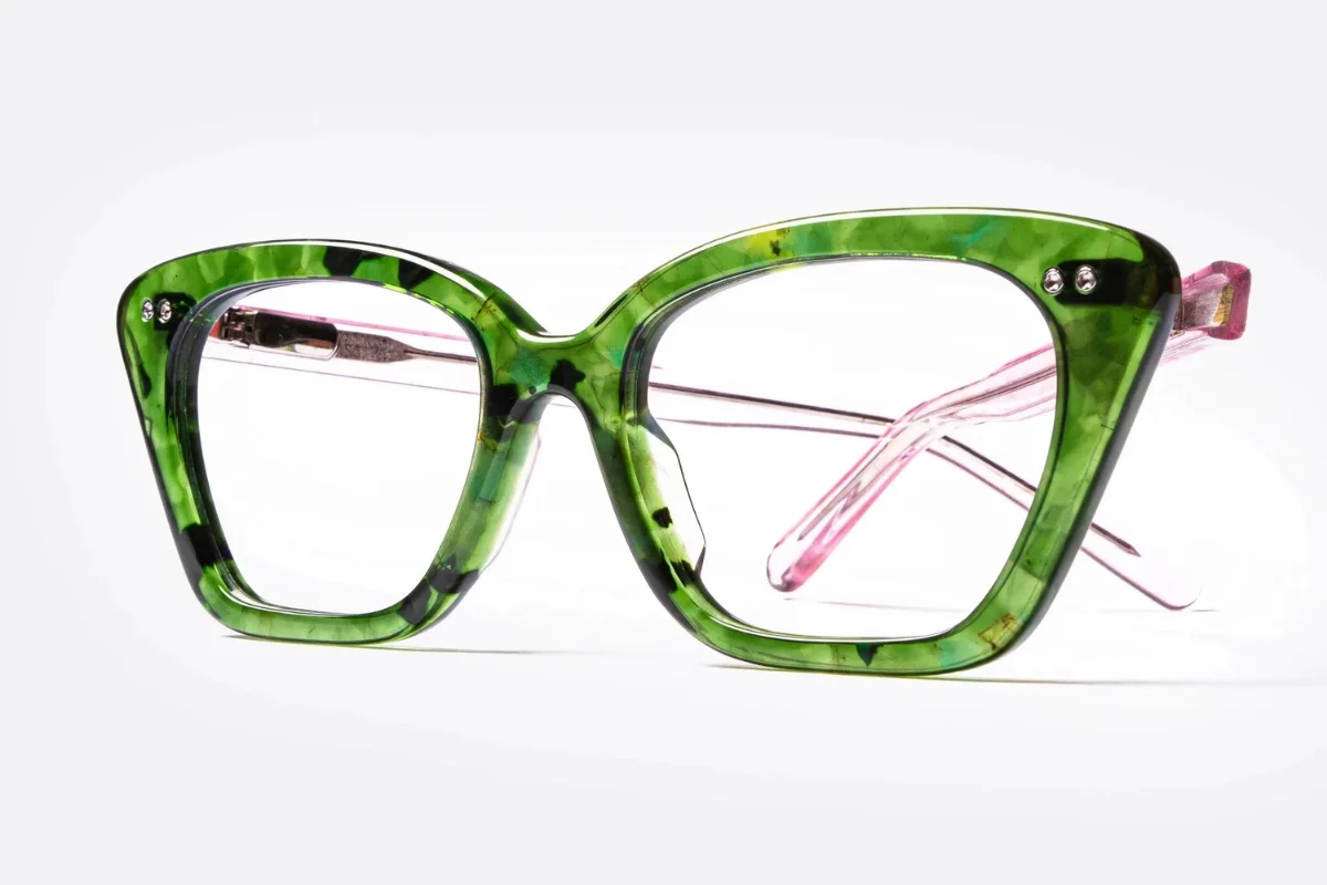 Green tortoiseshell cat-eye eyeglasses with pink temples on a white background.